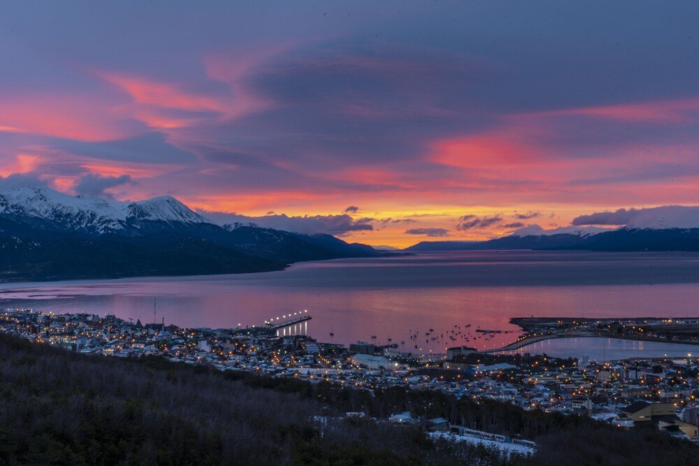 Coastal town at dusk with a bridge and mountains