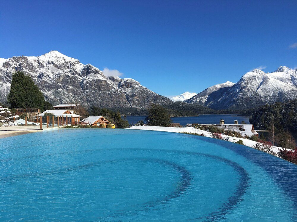 Resort with a swimming pool, wooden cabins and mountains behind